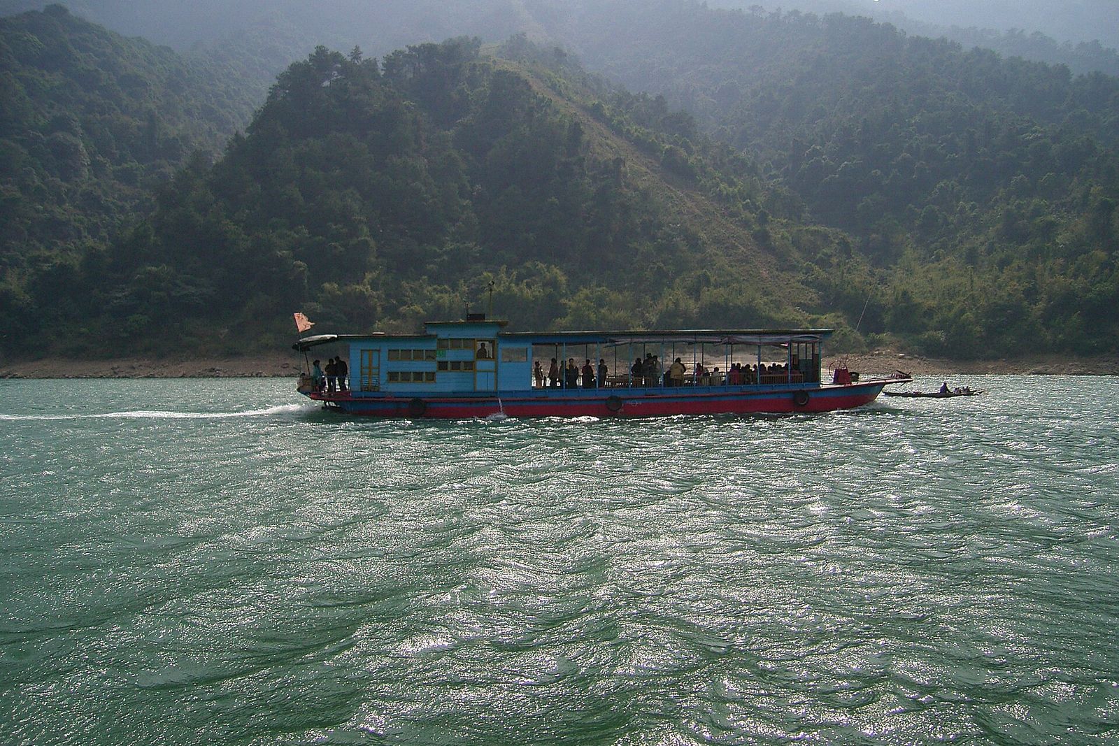 A boat on the Bei River below green hills at Qingyuan