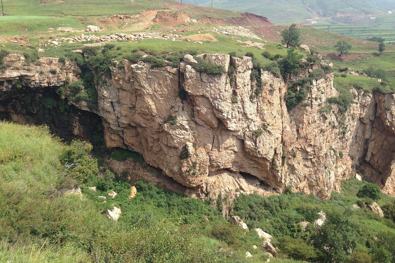 A cliff above a green hillside in Yu County, Zhangjiakou