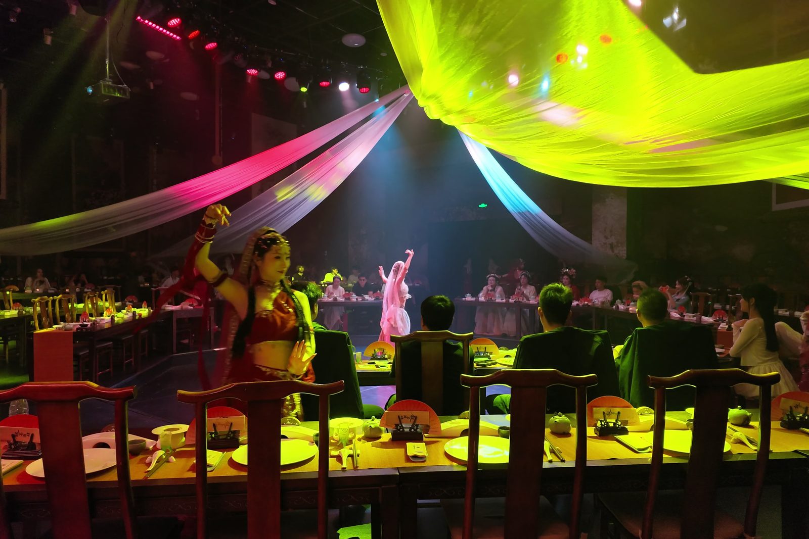 A dancer in a bright silk costume performing at a banquet theatre in Hangzhou