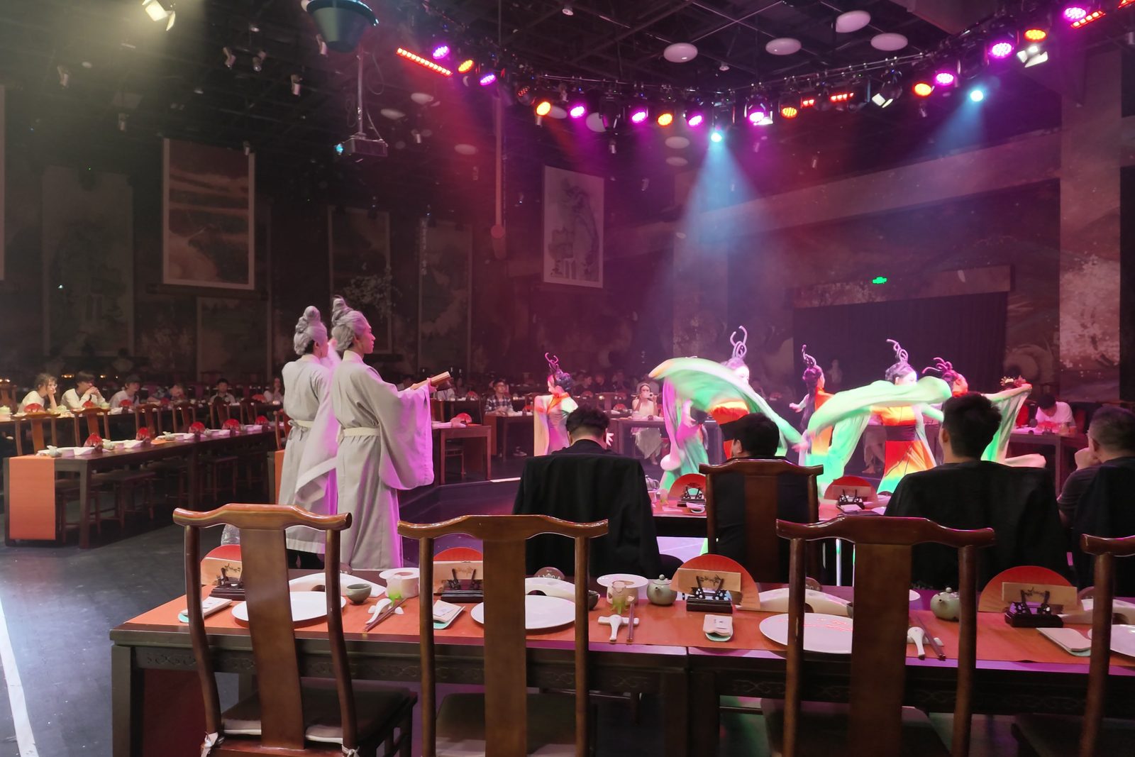 The stage of an immersive banquet theatre in Hangzhou with dancers in silk costumes and long dining tables